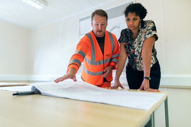 contractor in an orange reflective vest and a property owner looking at a blueprint